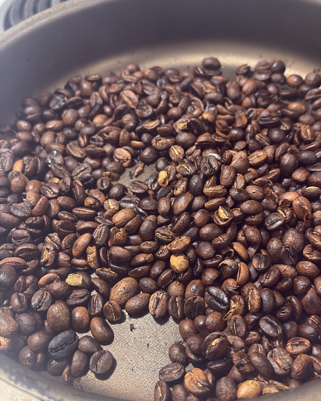 Granos de café tostándose en una sartén sobre la cocina